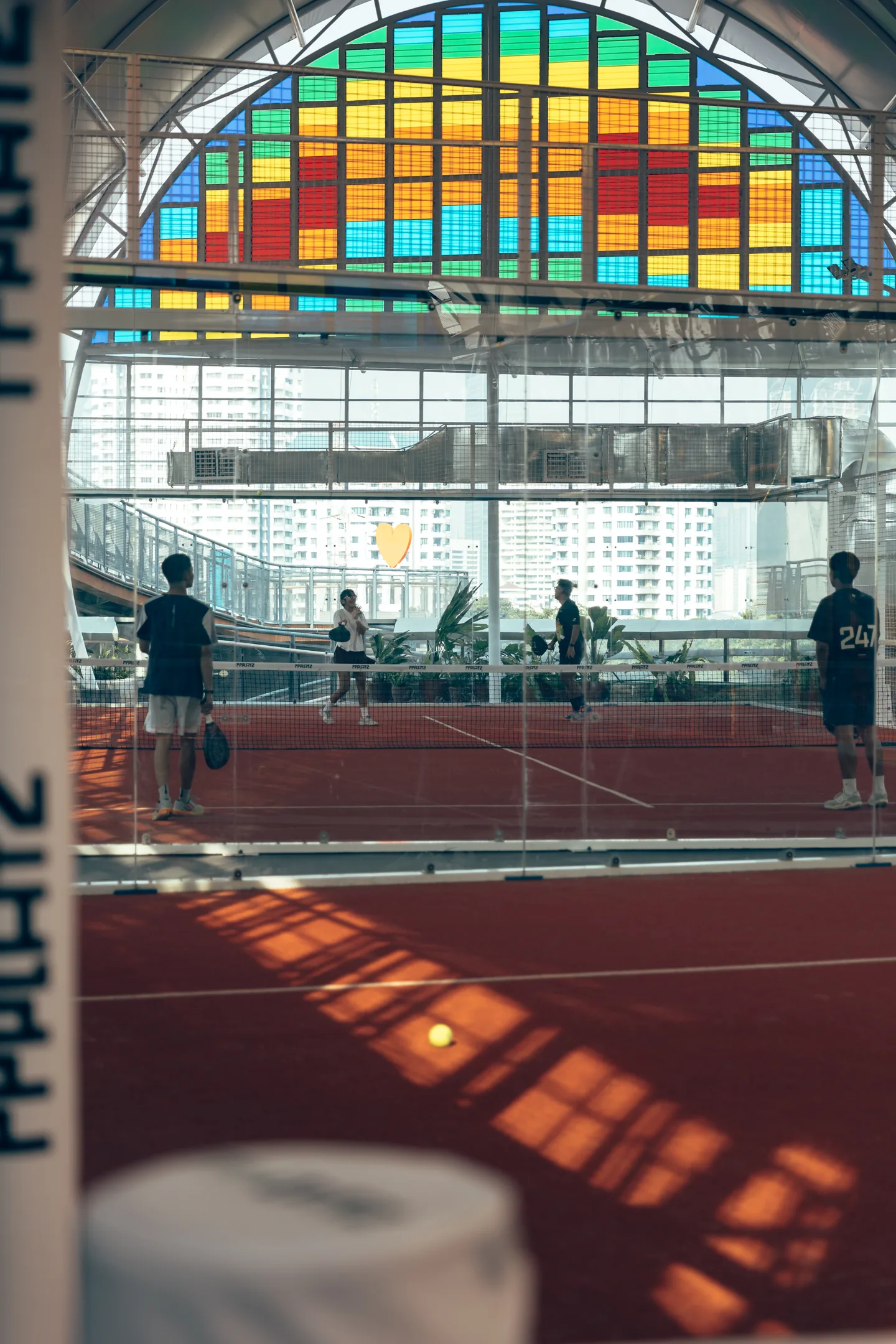 A game on the terracotta courts beneath PPPLATZ's multicoloured windows